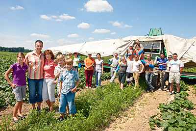 Betriebsleiter mit Familie und Team im Gemüsefeld