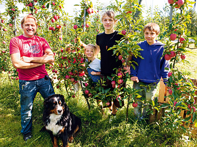 Betriebsleiter mit Kindern in Apfelplantage